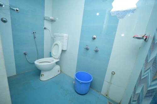 a blue bathroom with a toilet and a bucket at V stays in Kushālnagar