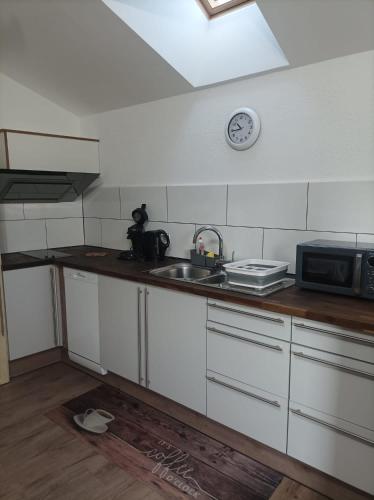 a kitchen with a sink and a clock on the wall at Casa Veli Apartments in Offenburg