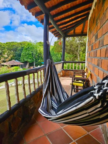 a hammock hanging on a porch of a house at Cabañas y Hostal Bonanza mesa de los santos in Los Santos