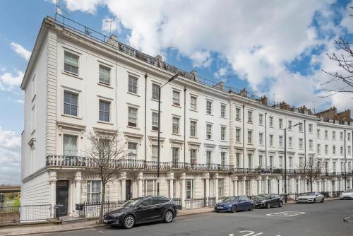 un gran edificio blanco con coches estacionados frente a él en BRAND NEW The Palms: Luxury Family Residence, en Londres