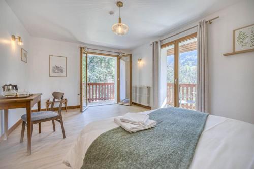 a bedroom with a bed and a desk and windows at Auberge du pont de l'Abîme in Gruffy