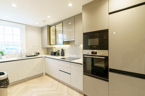 a kitchen with white cabinets and black appliances at Holland Park Residence in London