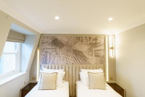 a bedroom with two beds with white pillows at Holland Park Residence in London