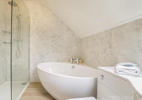 a white bathroom with a tub and a shower at Llysfaen Cottage in Cray