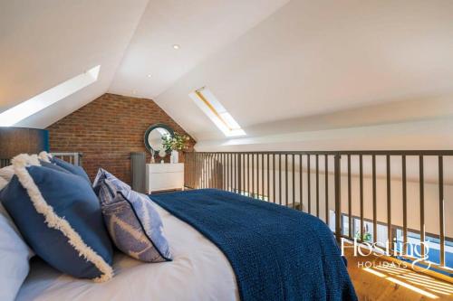 a bedroom with a large bed with blue pillows at The Evergreen Courtyard Henley-On-Thames in Henley on Thames