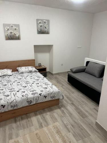 a bedroom with a bed and a couch in it at Apartman Kastel in Kaštela