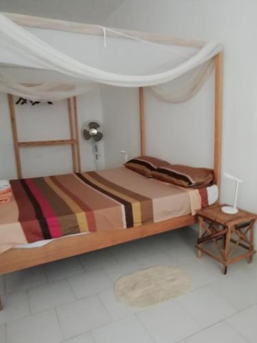 a bedroom with a bed with a canopy and a table at Chambre espacée et lumineuse in Mbour