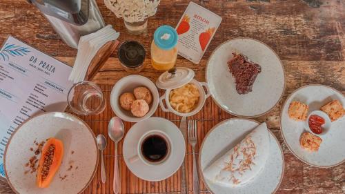 a wooden table with plates of food on it at Pousada Da Praia CARAIVA in Caraíva