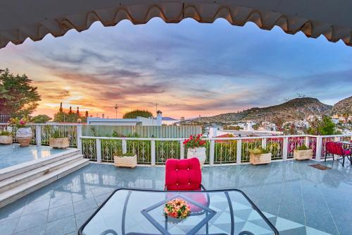 a patio with a glass table and chairs on a balcony at The Mardim Villa in Sounio