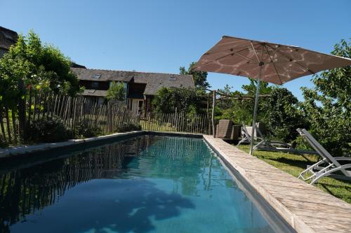 une piscine avec un parasol, une table et des chaises dans l'établissement Les hirondelles, à Saint-Bonnet-la-Rivière
