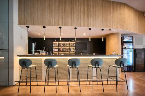 a kitchen with four stools at a bar at Catalonia Sabadell in Sabadell