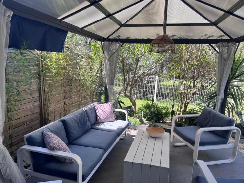 un patio avec un canapé bleu et deux chaises et un parasol dans l'établissement Grand Appartement T2, charmant jardin, à Montpellier