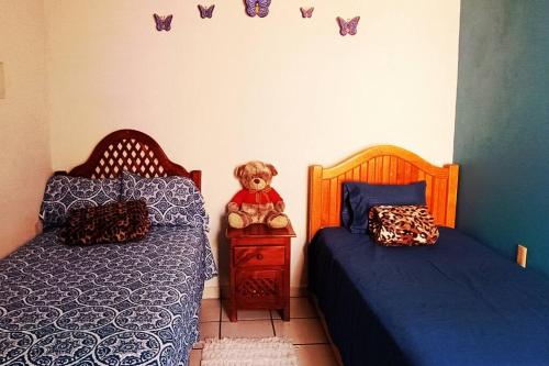 un dormitorio con 2 camas y un osito de peluche en una mesita de noche en La casa de Tita, en el sur de la Ciudad de México., en Ciudad de México