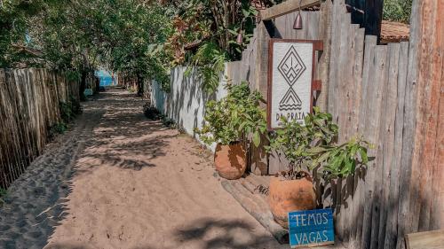 a fence with potted plants next to a dirt road at Pousada Da Praia CARAIVA in Caraíva