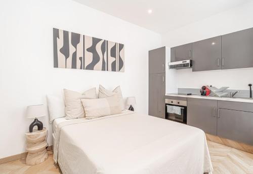 ein weißes Schlafzimmer mit einem Bett und einer Küche in der Unterkunft Nice Studio Close To Monaco in Beausoleil