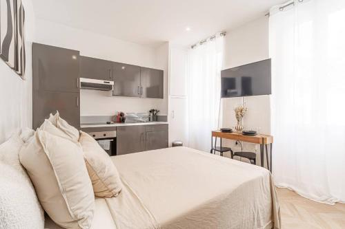 a white bedroom with a bed and a kitchen at Nice Studio Close To Monaco in Beausoleil