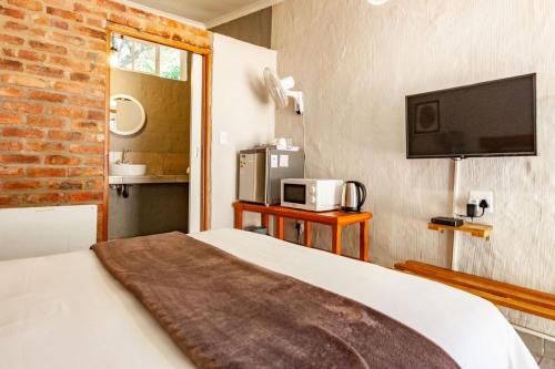 a bedroom with a bed and a tv on the wall at Waters on Willows in Pretoria