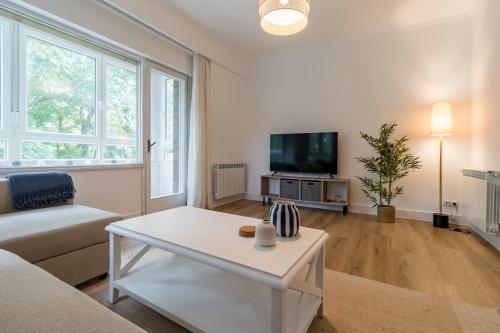 een woonkamer met een bank, een tafel en een tv bij Piso de diseño en el Sardinero in Santander