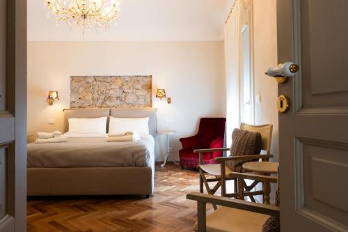 een slaapkamer met een bed, een stoel en een kroonluchter bij San Giuseppe apartment con Terrazza in Siracusa