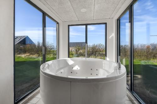 una gran bañera blanca en una habitación con ventanas en Pool house with beautiful view by the sea - SJ650, en Lemvig