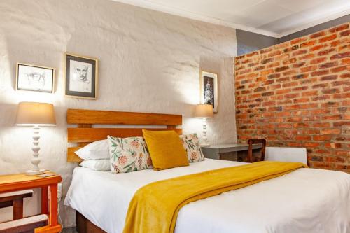 a bedroom with a bed and a brick wall at Waters on Willows in Pretoria