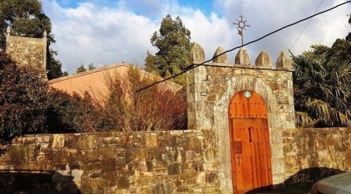 una iglesia con una puerta naranja y una pared de piedra en Ferienhaus für 9 Personen und 1 Kind in Lapido, Galicien Binnenland von Galicien, en Ortoño