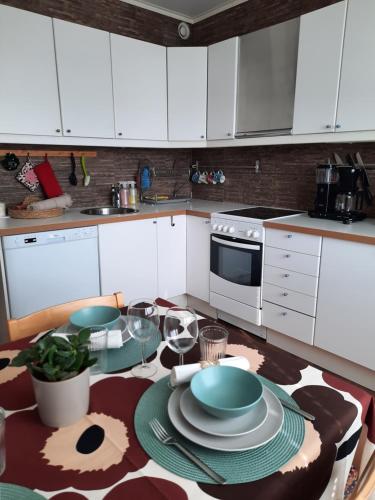una cocina con armarios blancos y una mesa con platos en Santa's Arctic Residence, en Rovaniemi