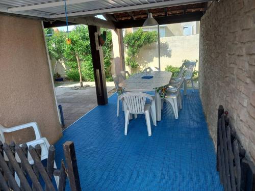 - une terrasse avec une table et des chaises sur un sol bleu dans l'établissement HOLIDAYLAND 233 T3 MEZZANINE 7 couchages climatisé NARBONNE PLAGE, à Narbonne-Plage