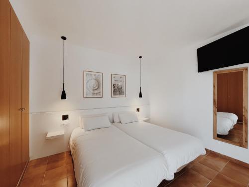a white bedroom with a large bed with white sheets at Hotel Bonaire in L'Escala
