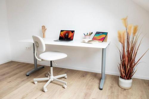 un escritorio blanco con una silla y un ordenador portátil. en Kassel Rooms en Kassel