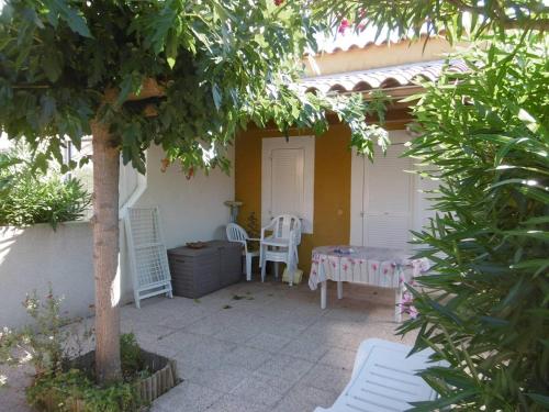 a patio with a table and chairs and a tree at HOLIDAYLAND 433 VILLA T2 MEZZANINE 6 couchages NARBONNE PLAGE in Narbonne-Plage