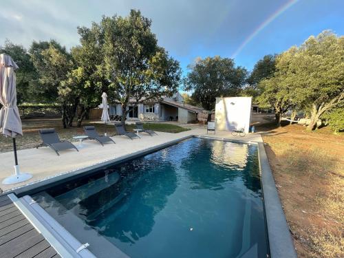 une piscine avec des chaises et un arc en arc-en-ciel en arrière-plan dans l'établissement Coeur de Lavande - Maison climatisée avec piscine, à Fox-Amphoux