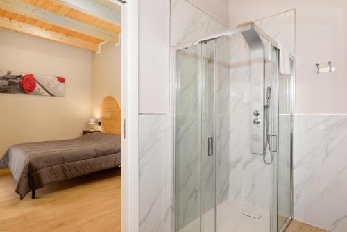 - une douche en verre dans une chambre avec un lit dans l'établissement Cascina Cavallo, à Canale