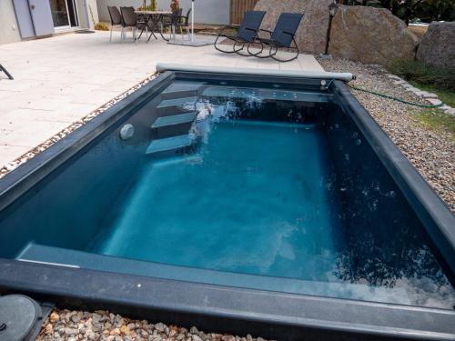 une piscine d'eau avec 2 chaises dans l'établissement Fleur de Romarin - Avec piscine privée, à Fox-Amphoux