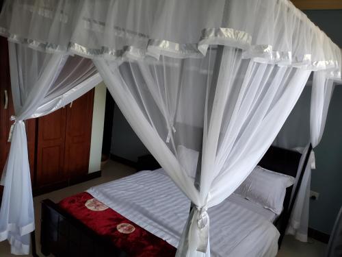 a bedroom with a canopy bed with white curtains at Bigodi Community Homestay in Kamwenge