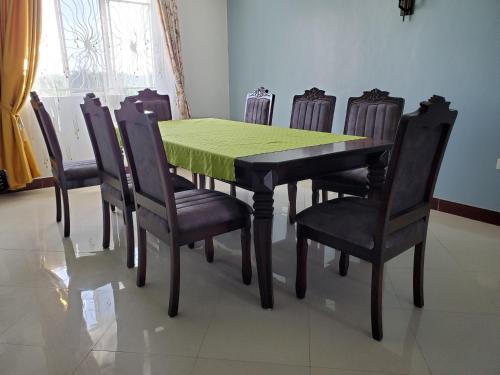 a dining room table with a green table and chairs at Bigodi Community Homestay in Kamwenge
