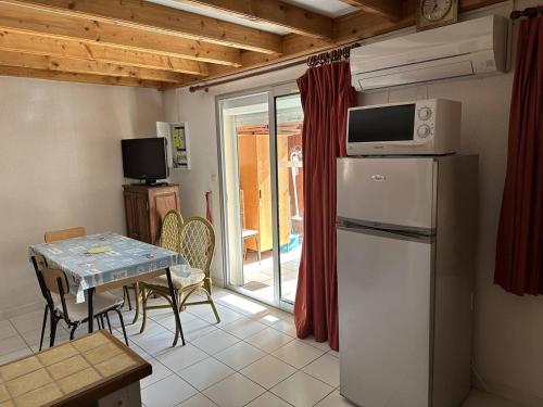 Il comprend une cuisine équipée d'un réfrigérateur et d'une table avec des chaises. dans l'établissement HOLIDAYLAND 127 VILLA T2 MEZZANINE 8 couchages climatisé avec véranda NARBONNE PLAGE, à Narbonne-Plage