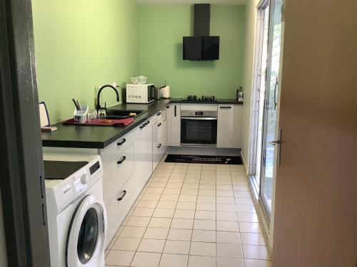 cocina con paredes verdes y suelo de baldosa blanca en Appartement 6 personnes Lamentin, en Le Lamentin