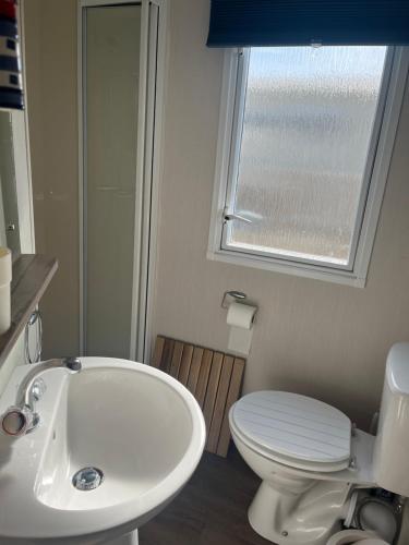a bathroom with a sink and a toilet and a window at Saltsea in Padstow