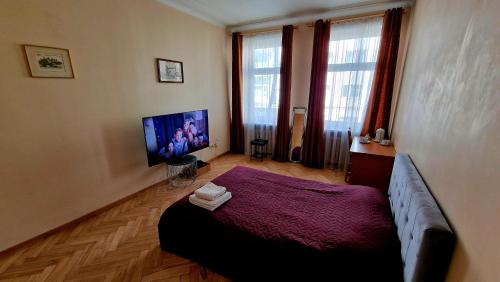 a bedroom with a bed and a flat screen tv at Kaunas Center Apartment in Kaunas