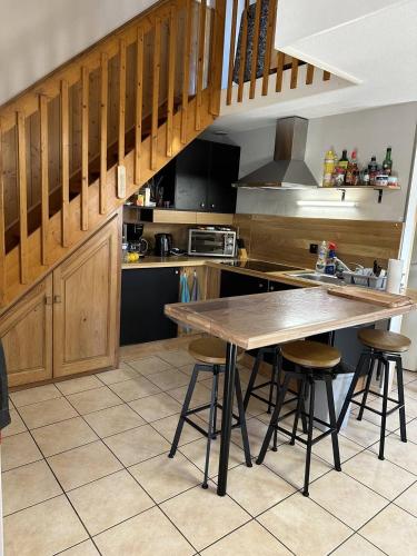 - une cuisine avec une table en bois et des tabourets dans l'établissement HOLIDAYLAND 441 VILLA T2 MEZZANINE 6 couchages avec véranda NARBONNE PLAGE, à Narbonne-Plage
