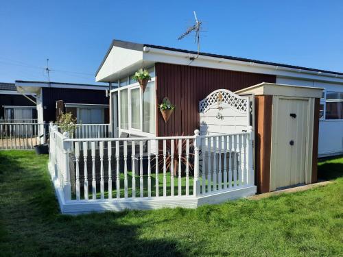 a white fence in front of a house at Family Tides-Chapel Saint Leonards in Chapel Saint Leonards