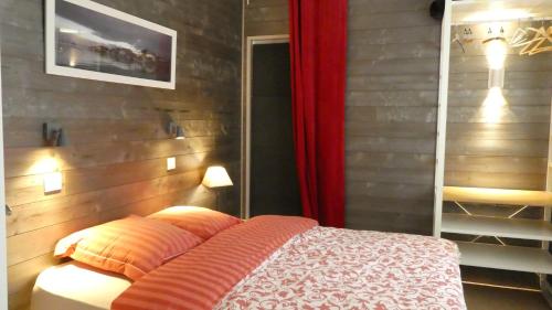 une chambre avec un lit et un rideau rouge dans l'établissement T2 au calme avec terrasse sur le bassin d'Arcachon, à Gujan-Mestras