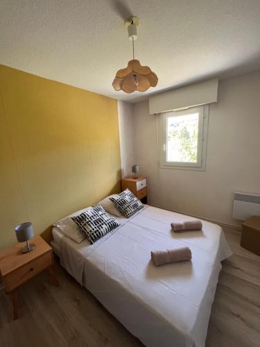 une chambre avec un grand lit blanc avec un ventilateur de plafond dans l'établissement Appartement Clim Terrasse, au Lavandou