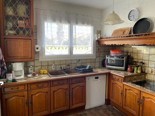 La cuisine est équipée de placards en bois, d'un évier et d'un four micro-ondes. dans l'établissement Maison proche de la mer, à Sainte-Marie-la-Mer