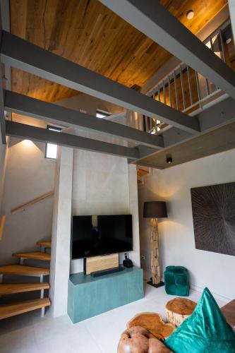 a living room with a flat screen tv and a staircase at SAUERLAND CHALETS - "Die Chalets Herzenssache" in Winterberg