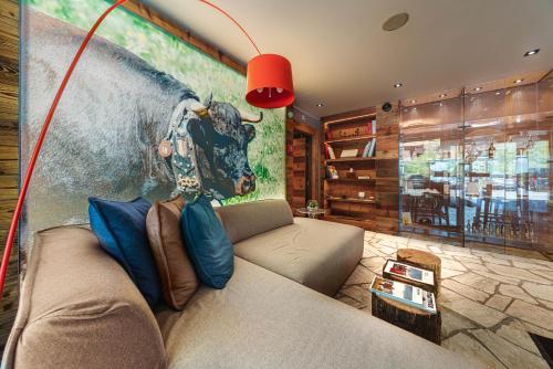 a living room with a couch and a painting of a cow at Chandolin Boutique Hotel in Chandolin