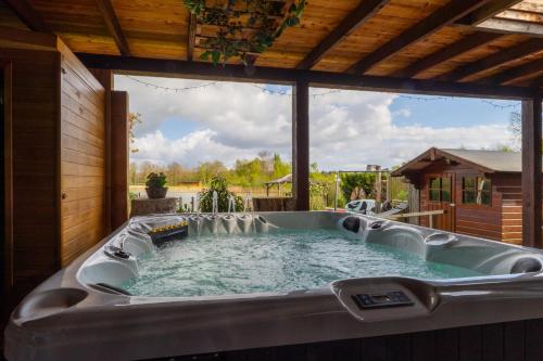 a hot tub in a backyard with a large window at Drents Genieten - Lavendelheide met uitzicht op het water in Erm