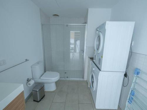 a white bathroom with a toilet and a refrigerator at Luxury Suite On Flinders Street in Melbourne