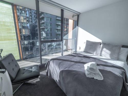 a bedroom with a bed and a chair and a window at Luxury Suite On Flinders Street in Melbourne
